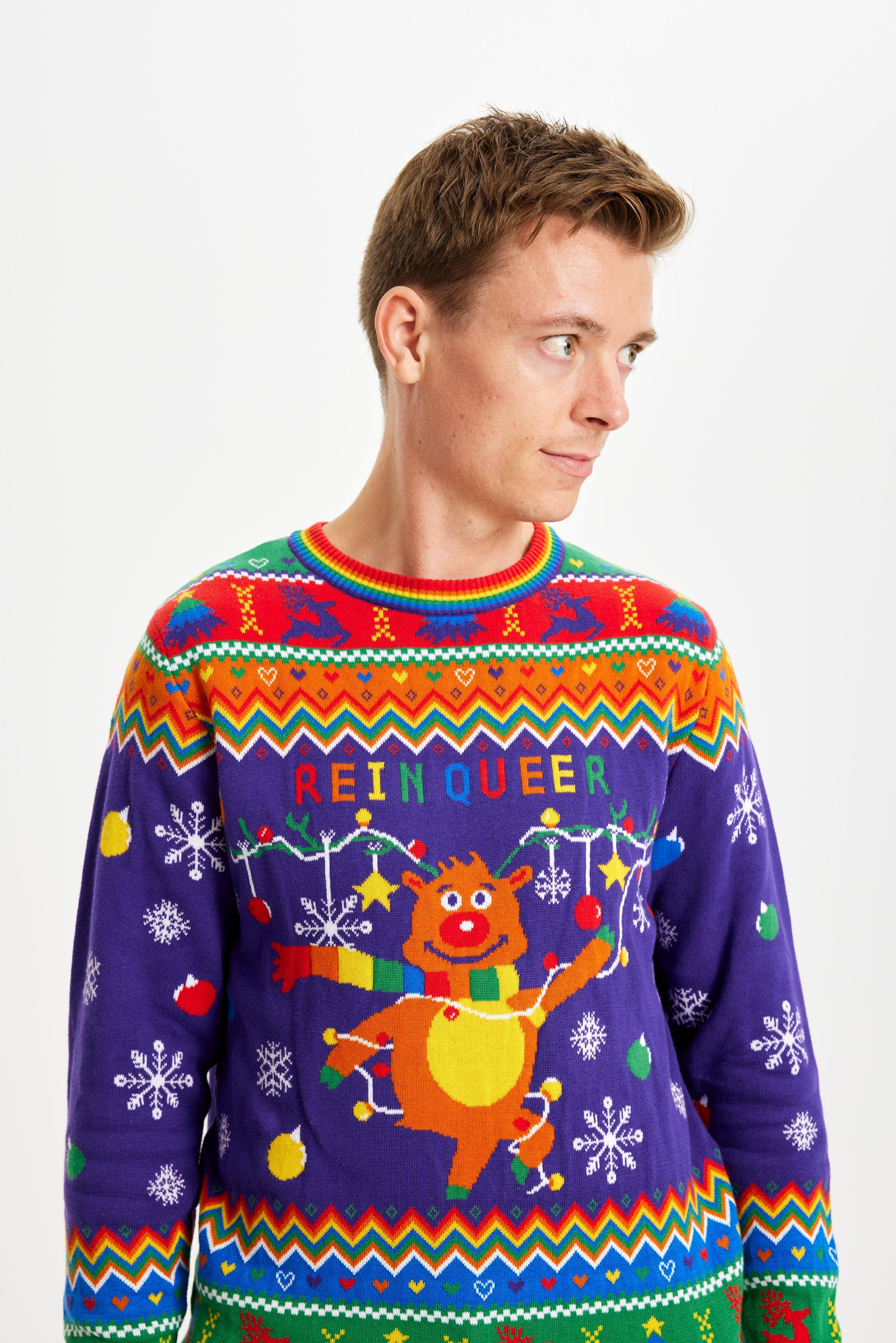 Een man die opzij kijkt en een regenboogkleurige kersttrui draagt met de quote 