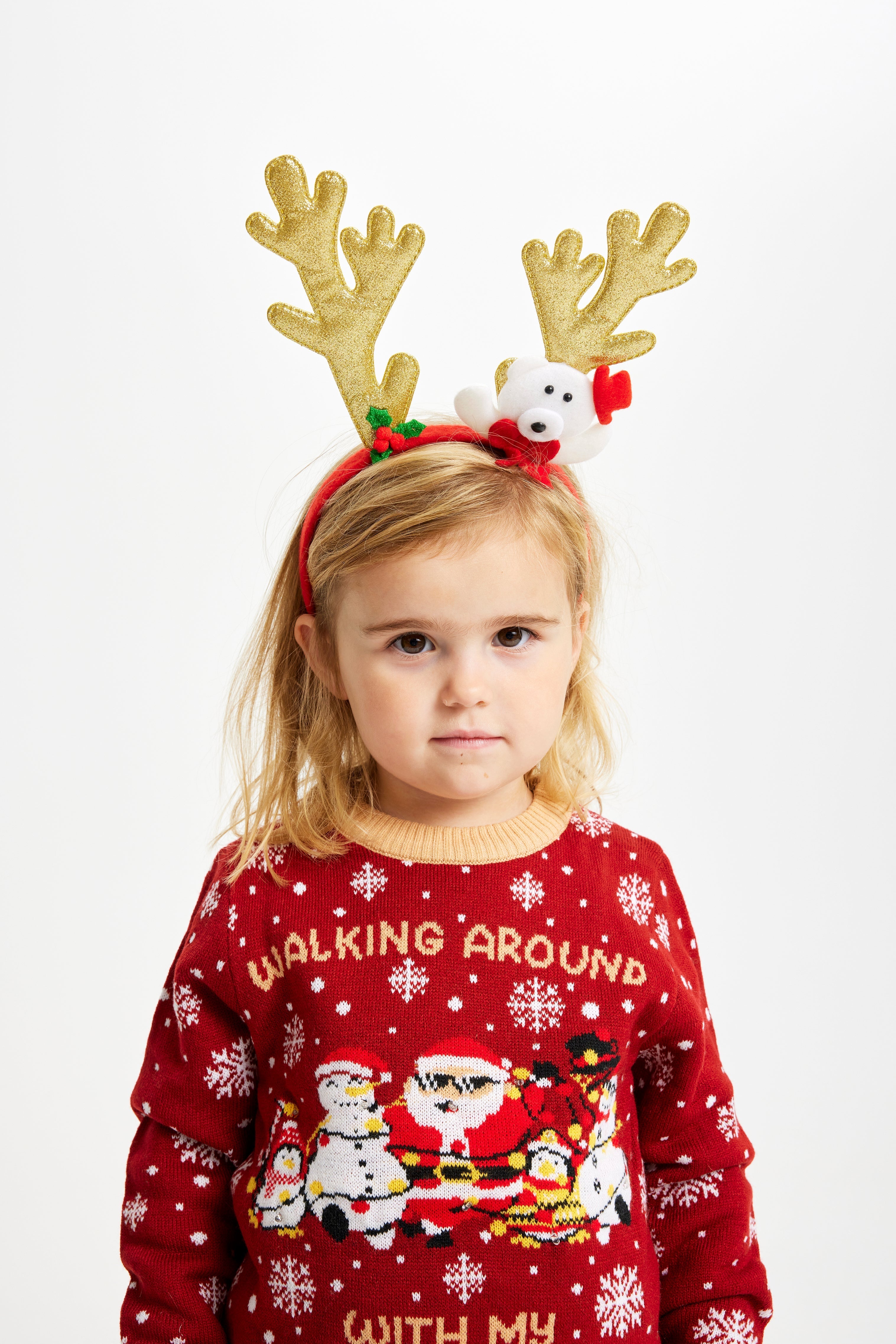 Een kind dat een rendiergewei draagt en een rode kersttrui met de quote 