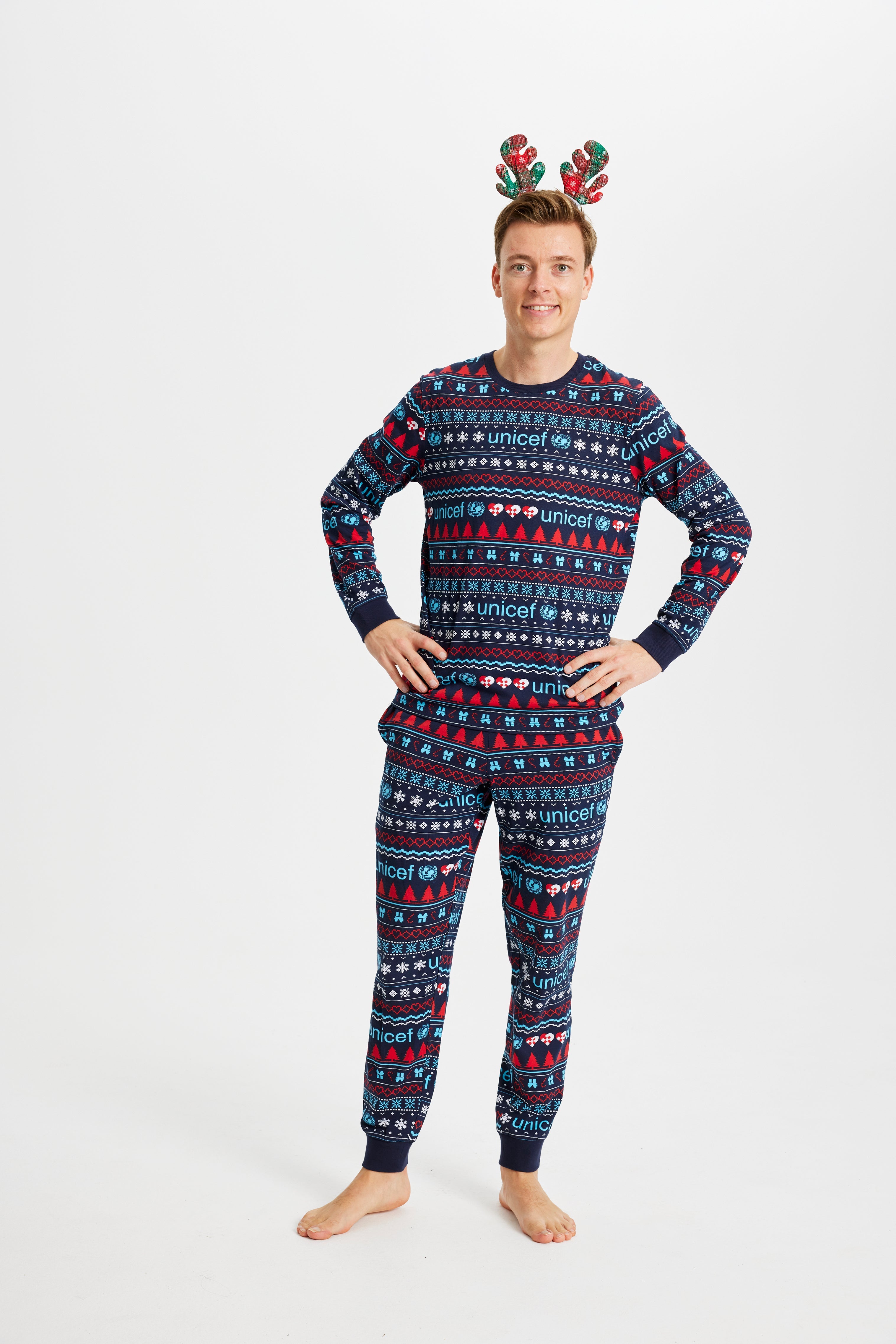 En mand med hænderne i siden iført blå julepyjamas.