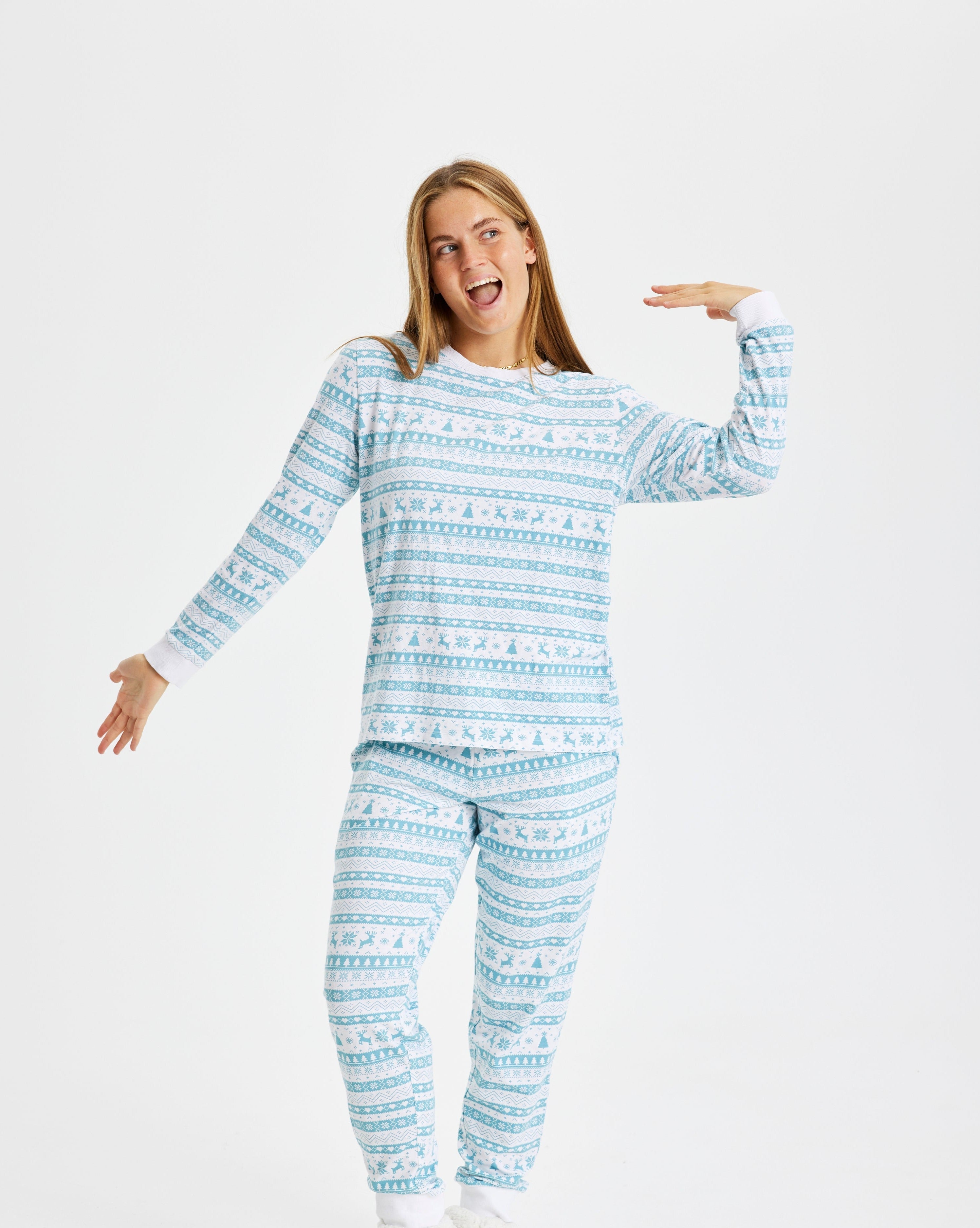 Een poserende vrouw in een lichtblauwe kerstpyjama.