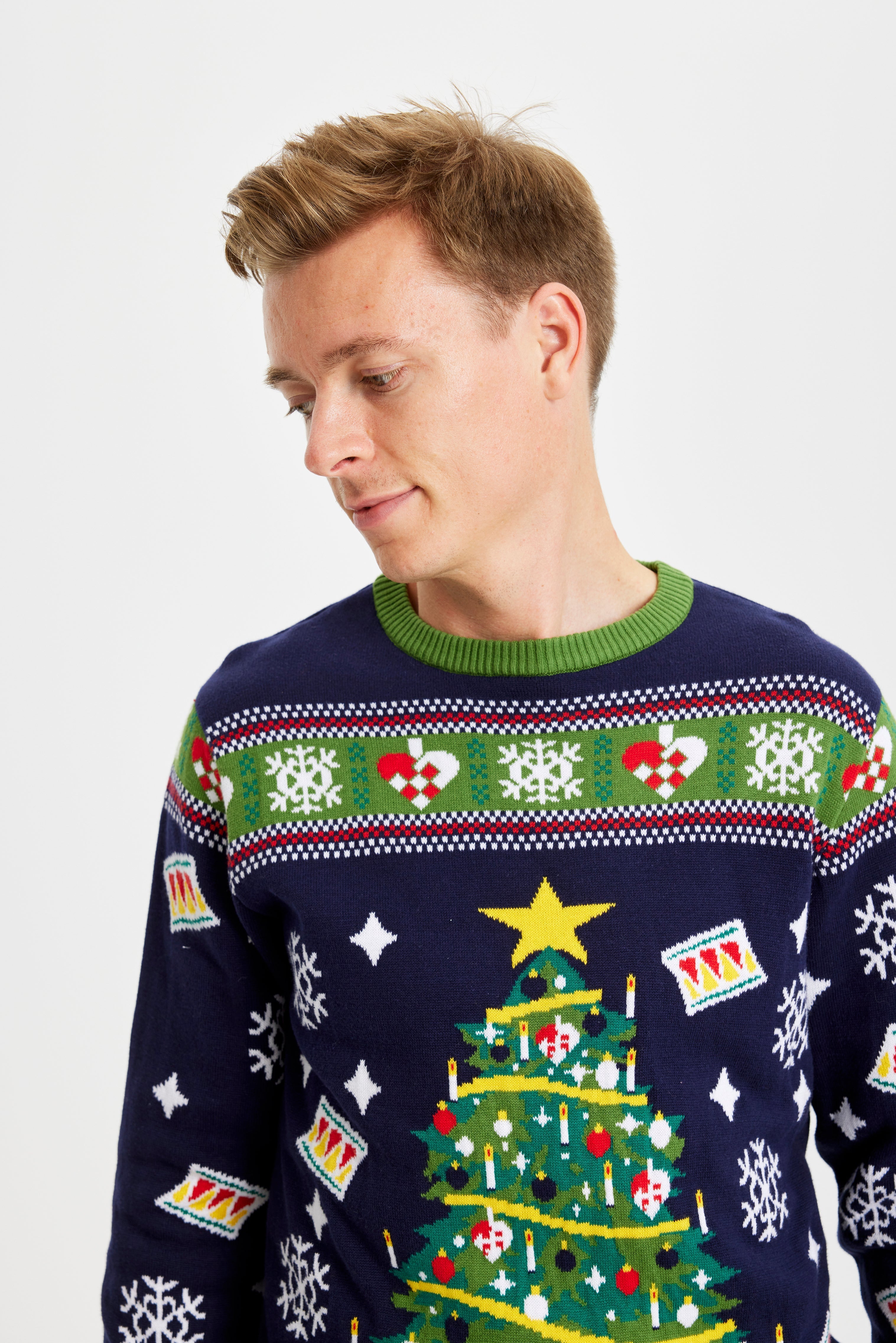 Een man die opzij kijkt en een blauwgroene met een knipperende kerstboom draagt.