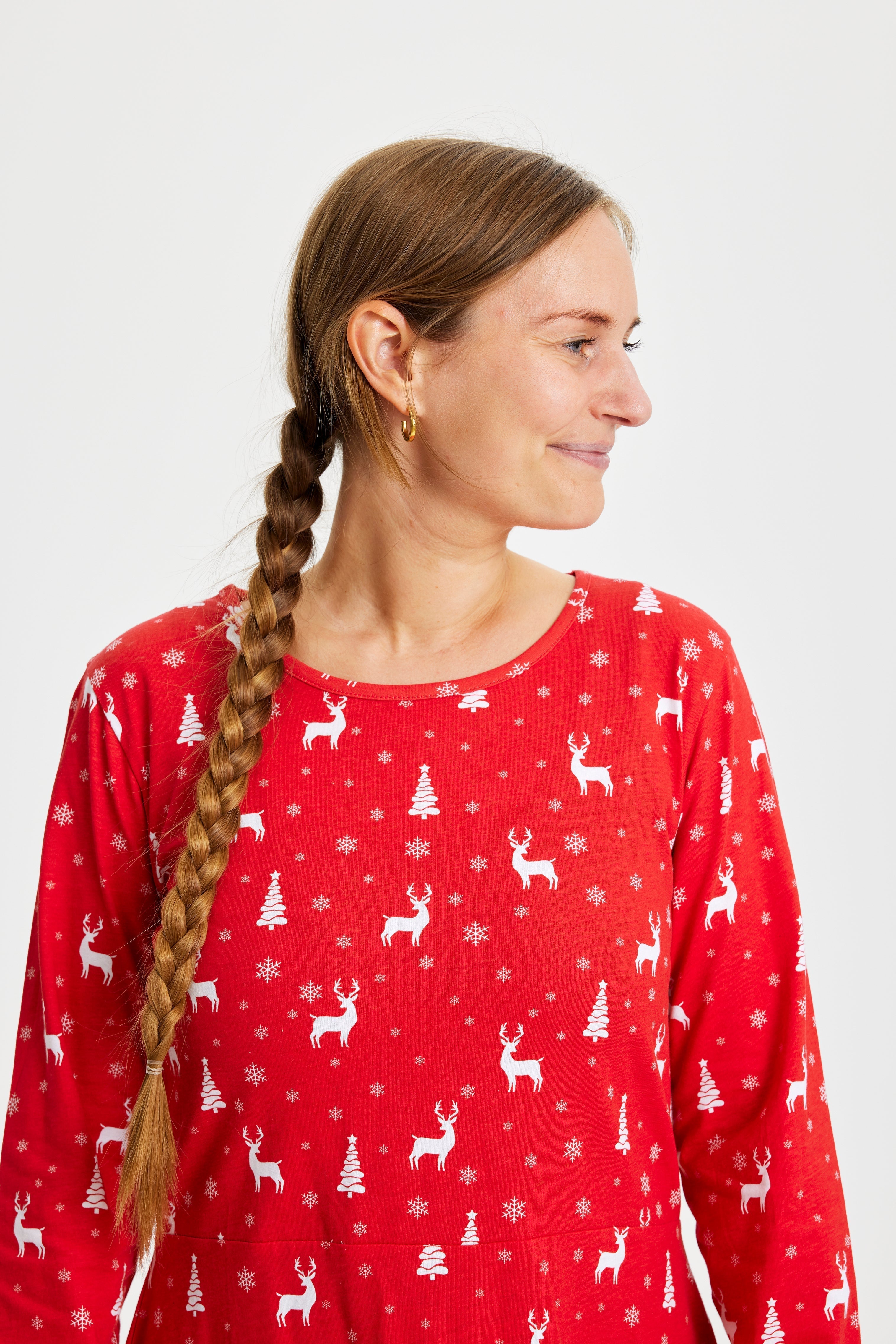 Een vrouw die opzij kijkt en een rode kerstjurk draagt.