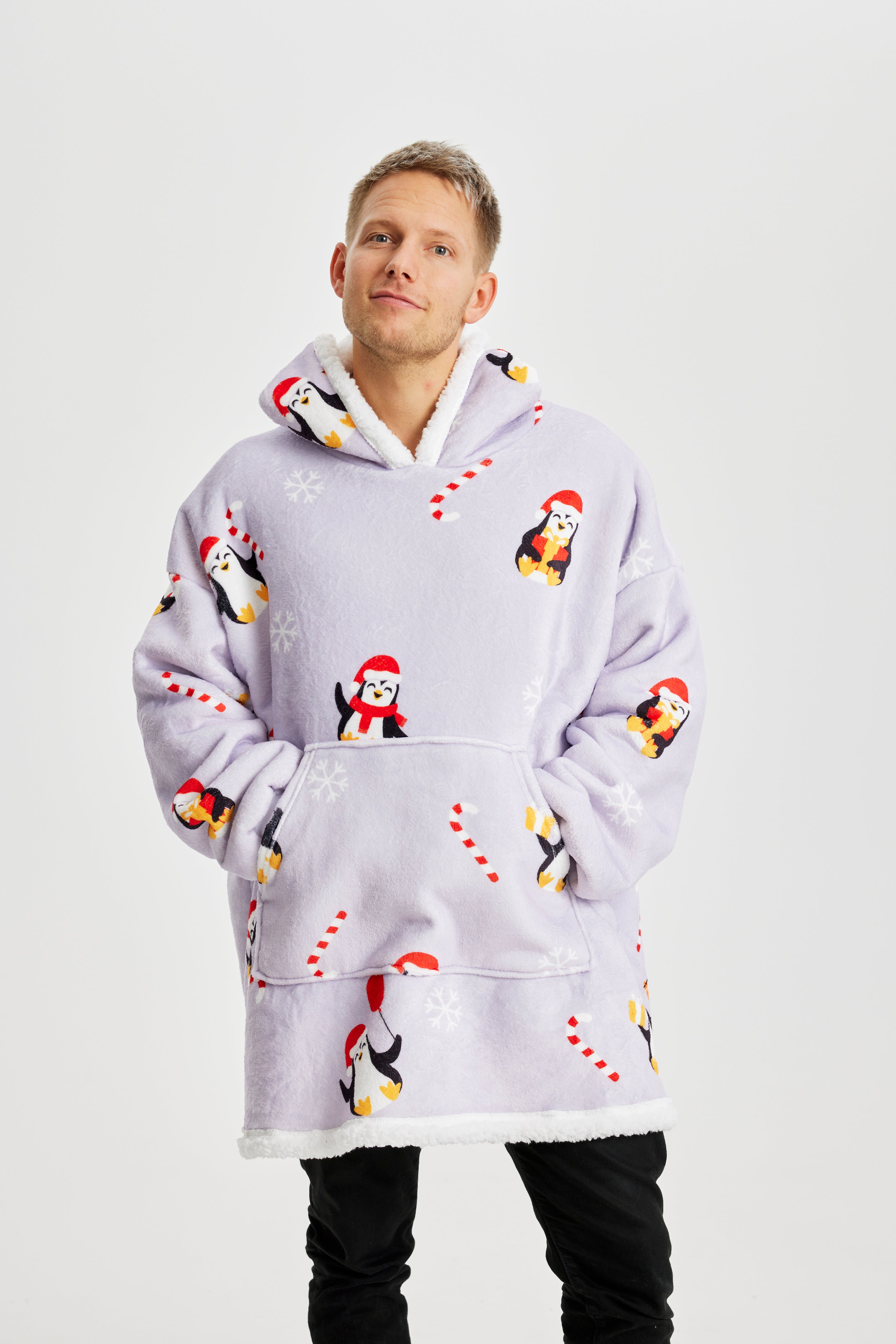 Een man die een lichtpaarse kerst hoodie met pinguïns draagt.