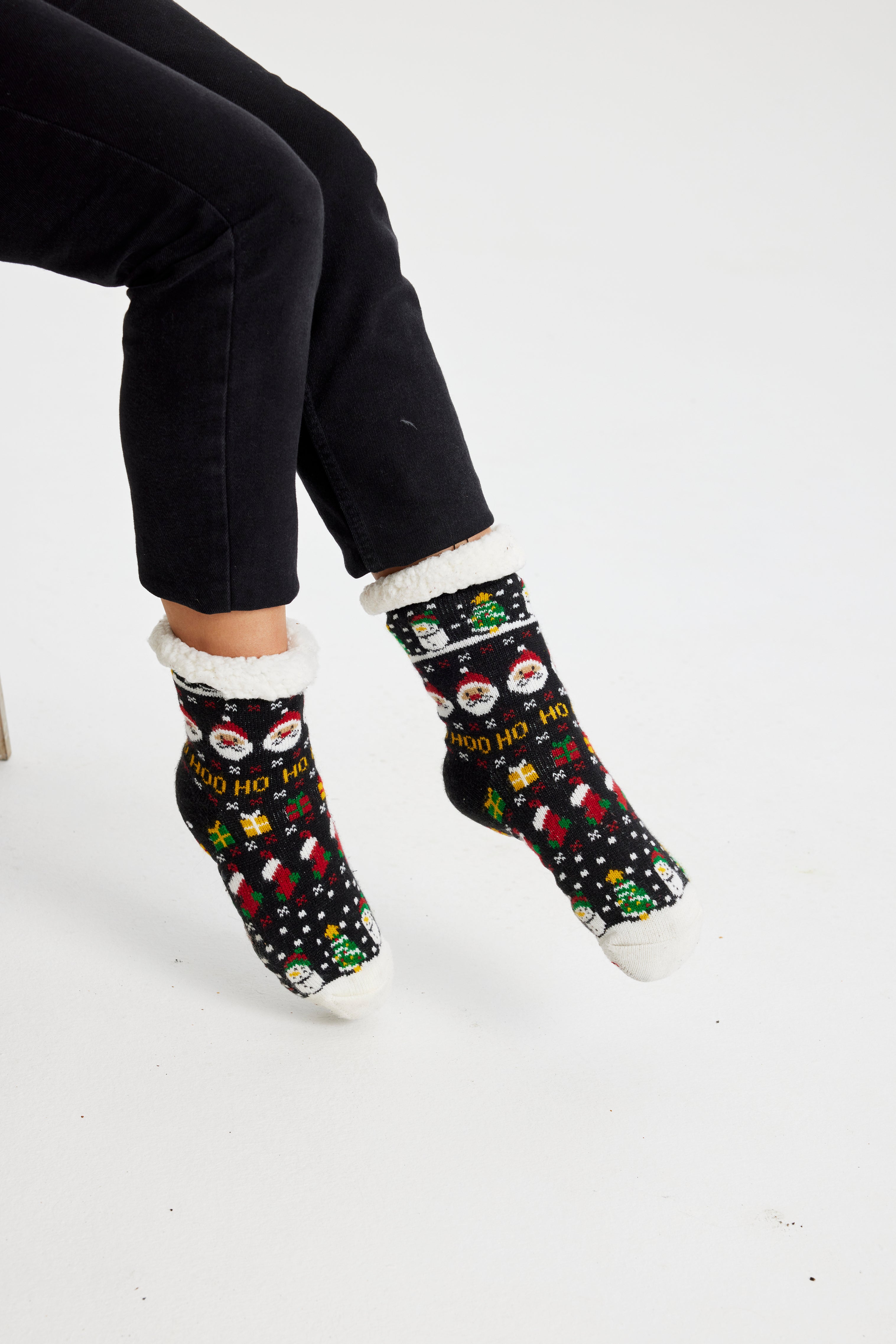 Een paar benen die zwarte kerstsokken dragen met een patroon erop.