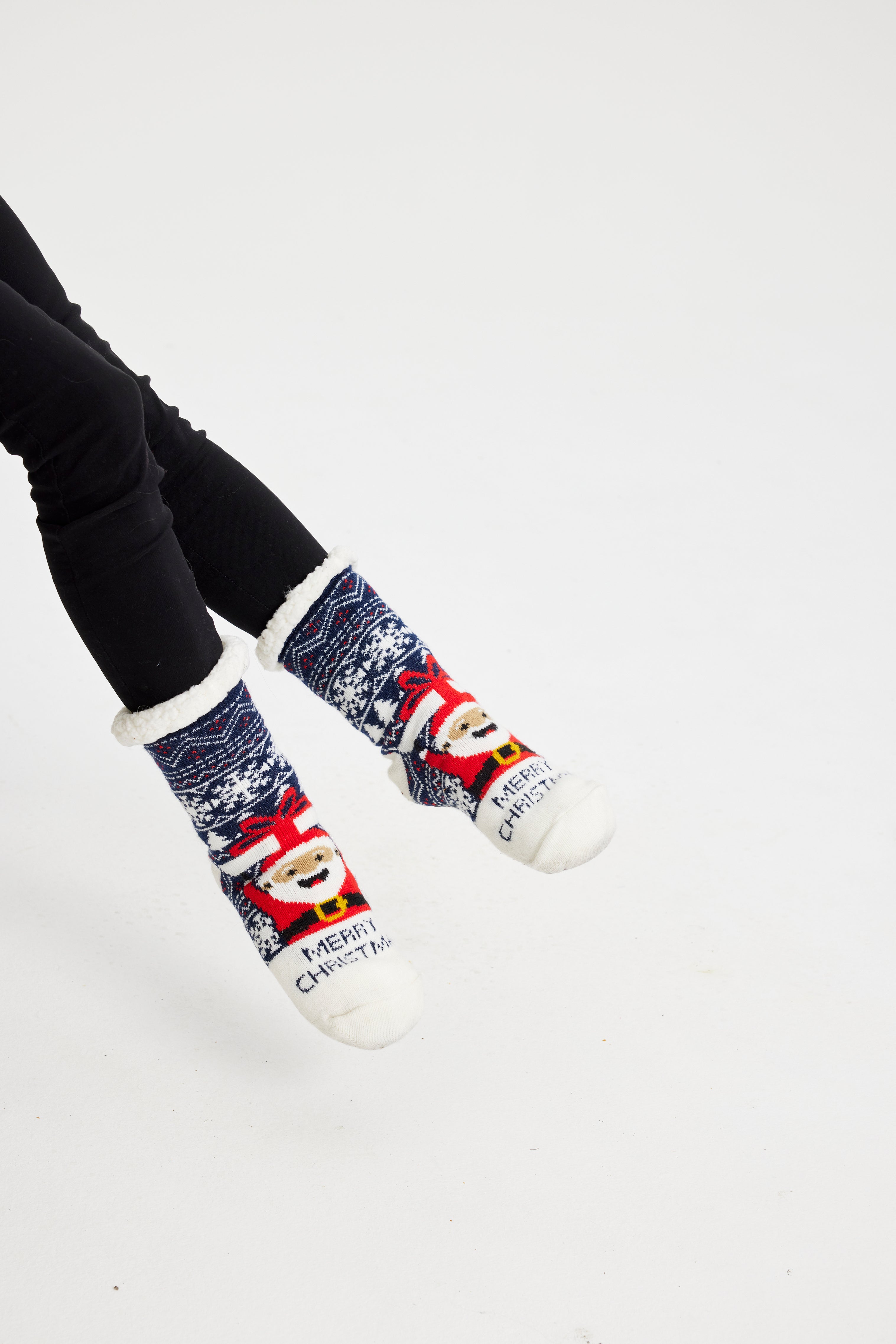 Een paar benen met blauwe kerstsokken met de kerstman erop.