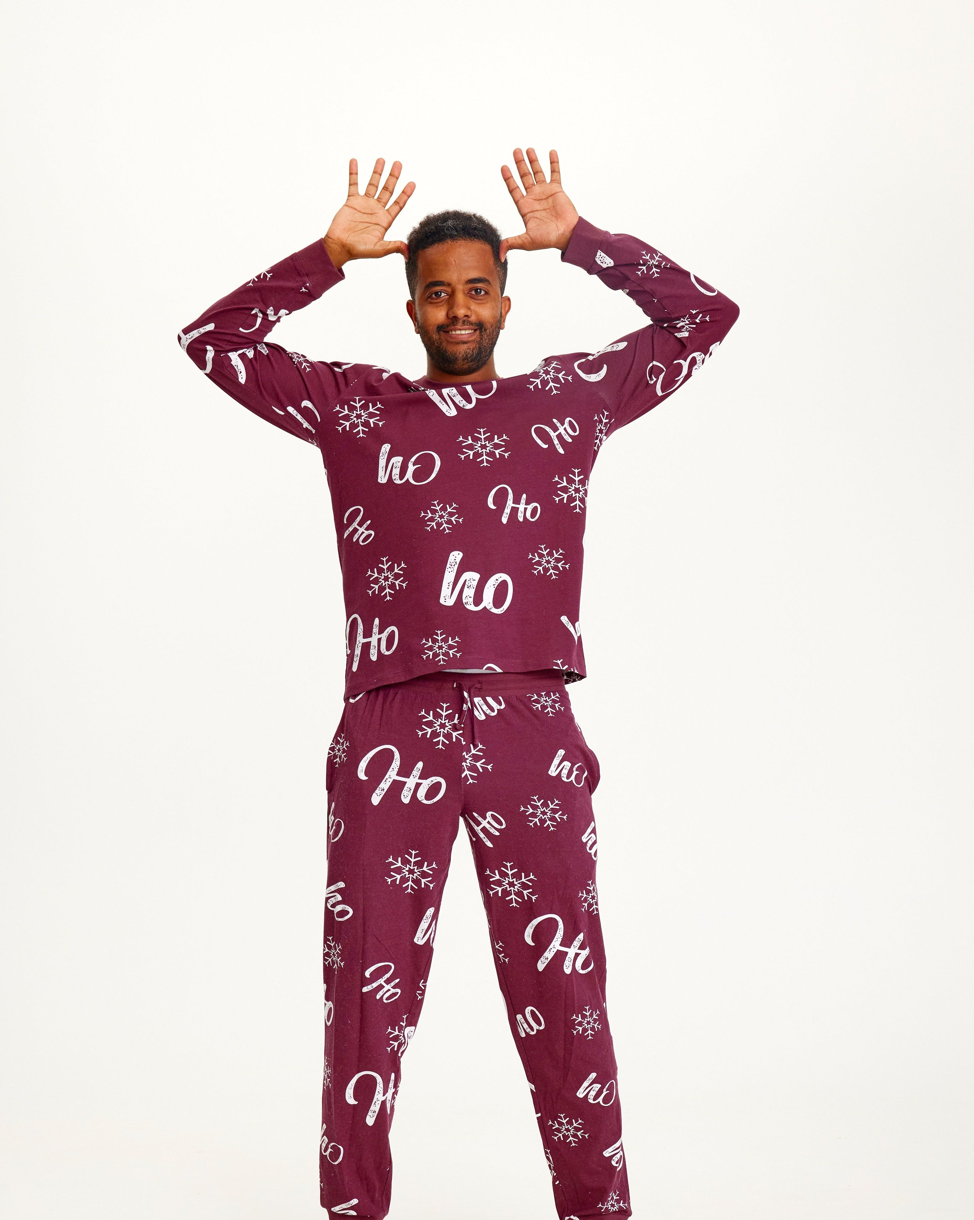 Een man die een donkerrode kerstpyjama draagt.